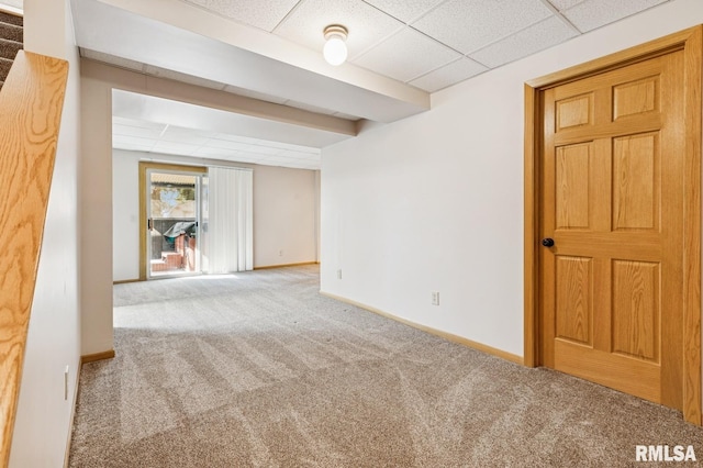 below grade area with carpet floors, baseboards, and a drop ceiling