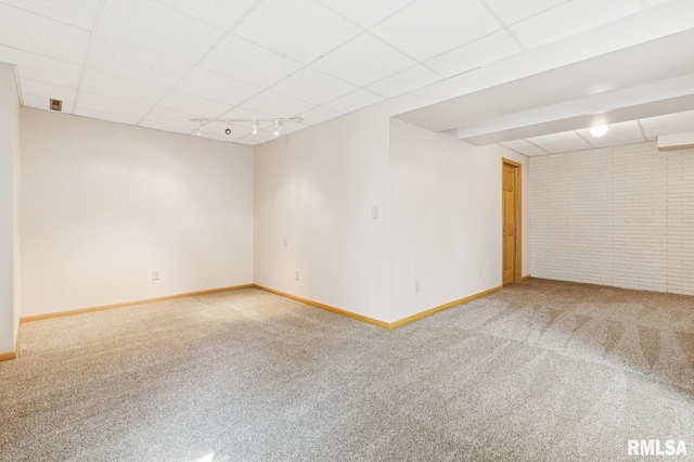 unfurnished room with baseboards, carpet floors, a drop ceiling, and track lighting