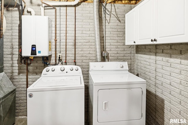 laundry room with cabinet space, tankless water heater, and washer and dryer