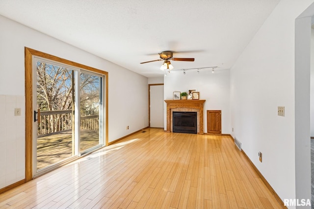 unfurnished living room featuring baseboards, visible vents, a ceiling fan, light wood-style floors, and a fireplace