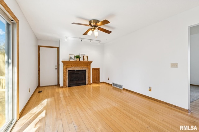 unfurnished living room featuring light wood-style flooring, visible vents, baseboards, and a tile fireplace