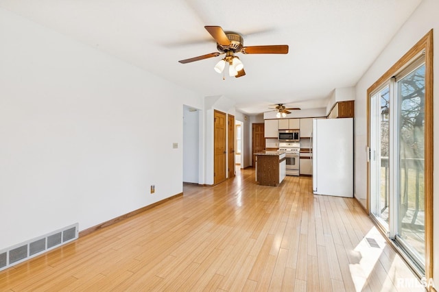 unfurnished living room with baseboards, visible vents, and light wood finished floors