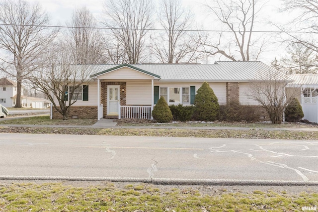 single story home featuring crawl space, a porch, metal roof, and brick siding