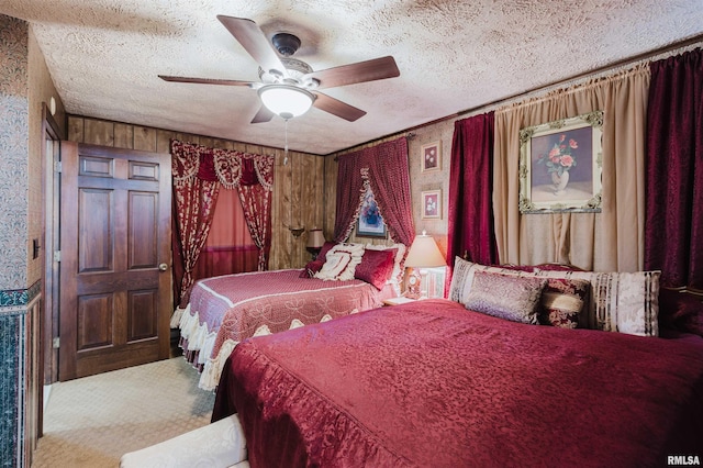 carpeted bedroom featuring a ceiling fan, wood walls, and a textured ceiling