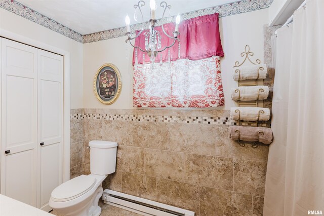 full bath featuring a notable chandelier, tile walls, toilet, a baseboard heating unit, and wainscoting