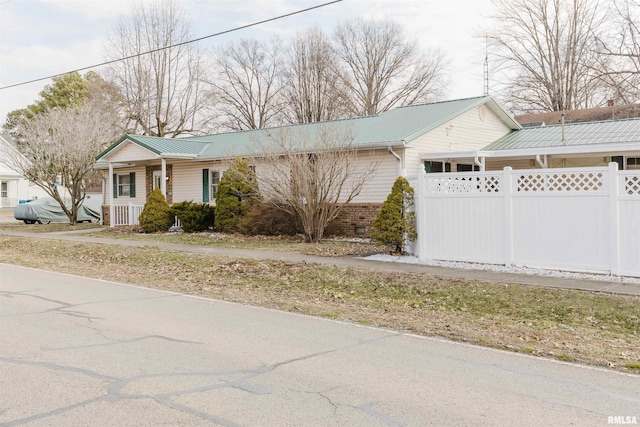 ranch-style home featuring metal roof and fence