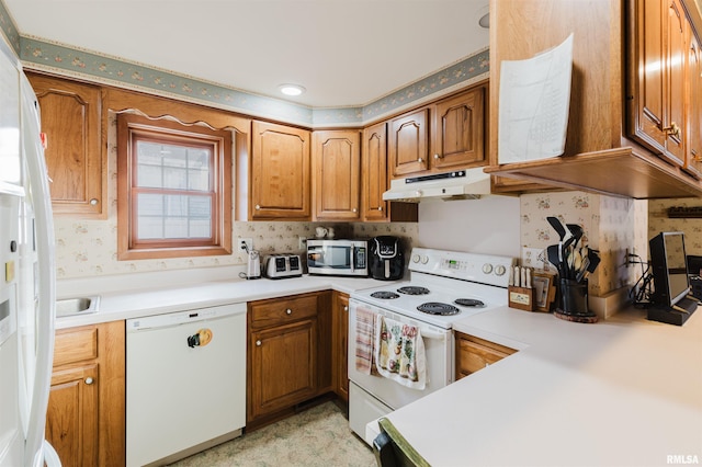 kitchen with light countertops, white appliances, brown cabinetry, and under cabinet range hood