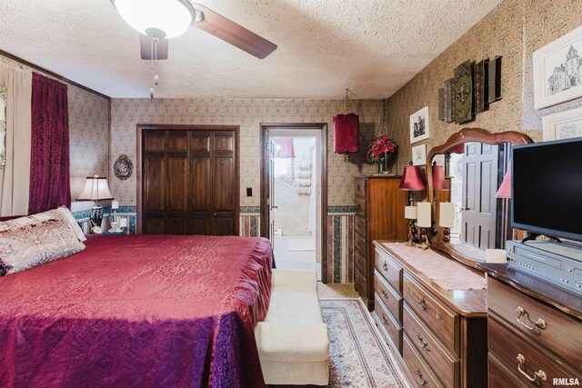 bedroom with a textured ceiling, ensuite bathroom, and wallpapered walls