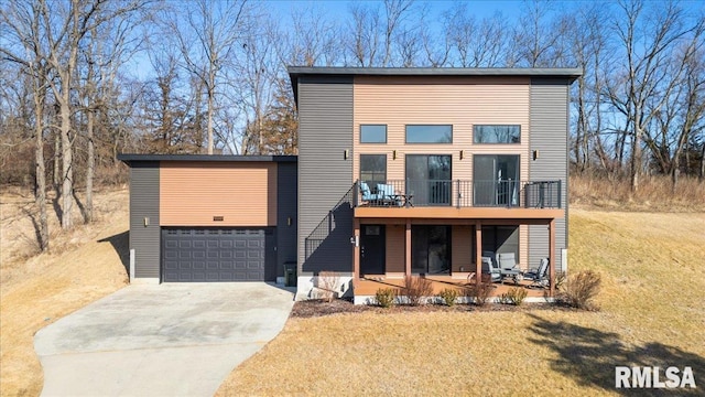 contemporary house featuring driveway, a front lawn, an attached garage, and a balcony