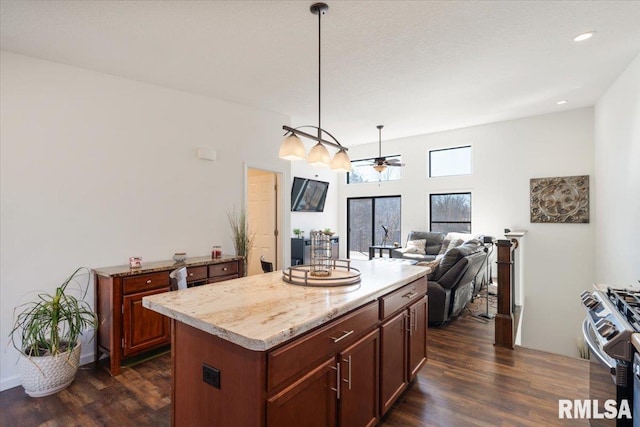 kitchen featuring stainless steel gas stove, a kitchen island, dark wood finished floors, and a ceiling fan