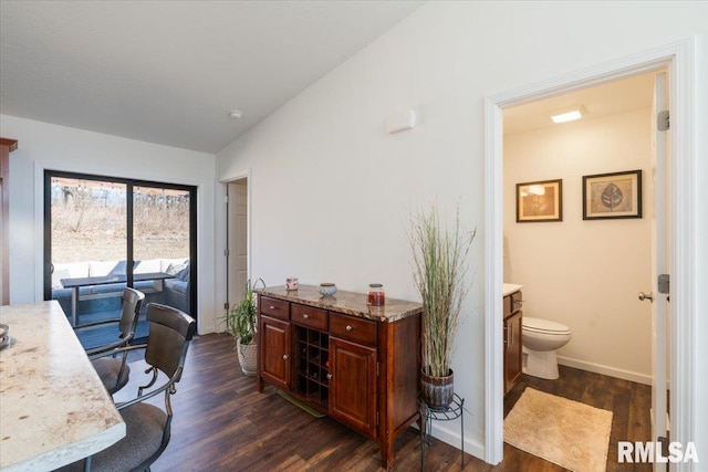 office area featuring vaulted ceiling, baseboards, and dark wood finished floors