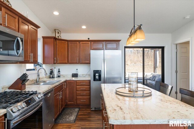 kitchen with appliances with stainless steel finishes, dark wood-style flooring, a center island, a sink, and recessed lighting