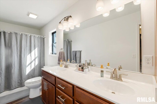 full bath with toilet, double vanity, a sink, and a shower with shower curtain