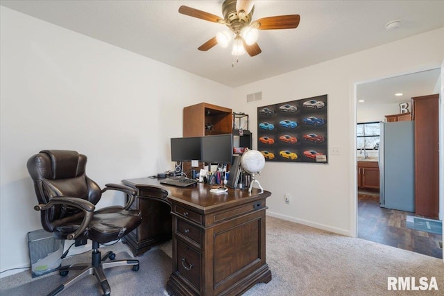 carpeted office space with baseboards, visible vents, and a ceiling fan