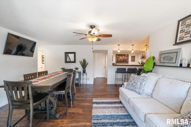 living room featuring ceiling fan, baseboards, dark wood finished floors, and a textured ceiling