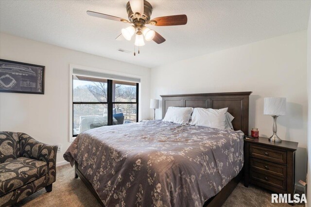 bedroom with a textured ceiling, dark carpet, visible vents, and a ceiling fan