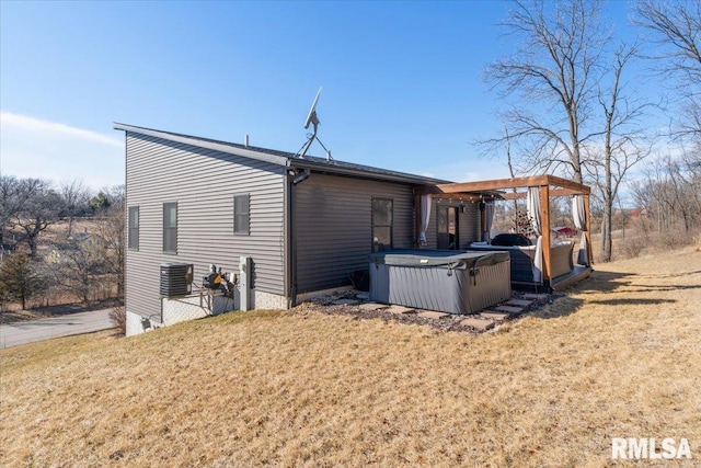 view of side of home with a hot tub, cooling unit, and a yard