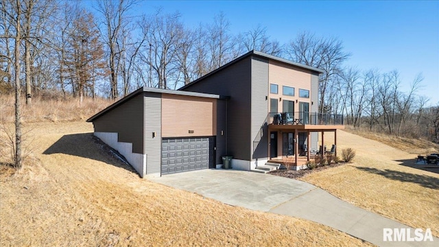 contemporary home with driveway, a front lawn, an attached garage, and a balcony