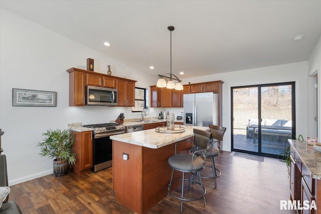 kitchen featuring a sink, appliances with stainless steel finishes, a wealth of natural light, a center island, and dark wood finished floors