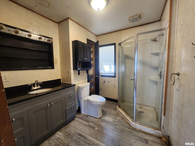 bathroom with crown molding, wood finished floors, visible vents, and tile walls