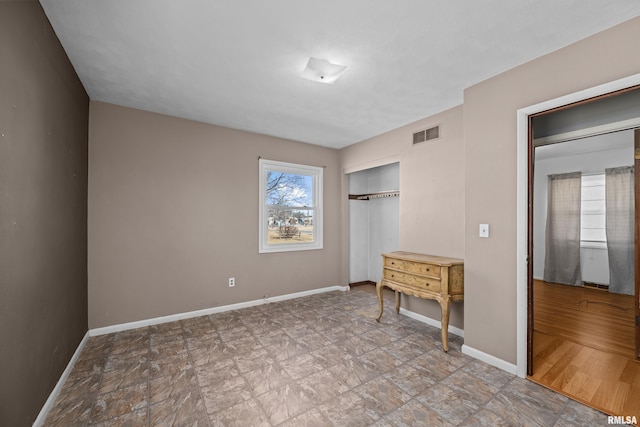 unfurnished bedroom with a closet, visible vents, and baseboards