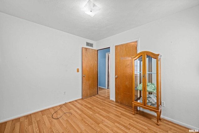 unfurnished room featuring visible vents, baseboards, and wood finished floors