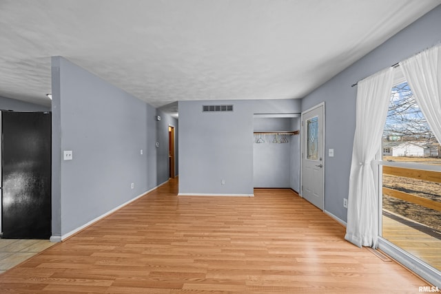 unfurnished room with light wood finished floors, baseboards, and visible vents