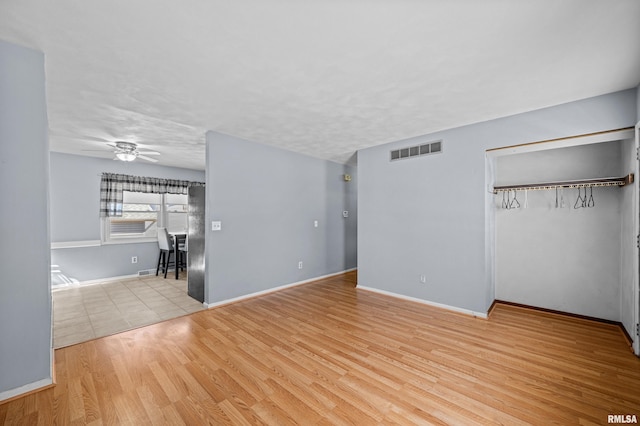 unfurnished living room featuring a textured ceiling, wood finished floors, visible vents, baseboards, and a ceiling fan