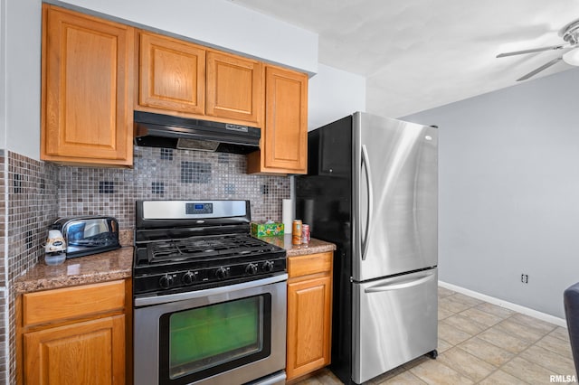 kitchen featuring appliances with stainless steel finishes, stone counters, under cabinet range hood, and decorative backsplash