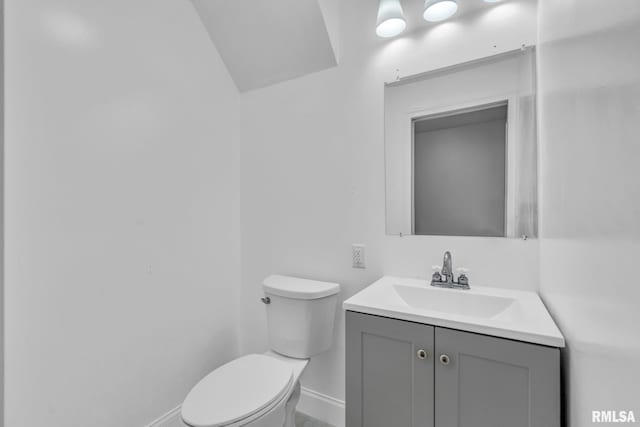 half bathroom featuring toilet, baseboards, and vanity