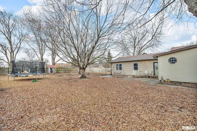 view of yard with a trampoline, fence, and a patio