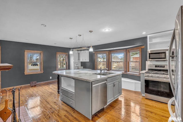 kitchen featuring stainless steel appliances, gray cabinets, a center island with sink, and open shelves