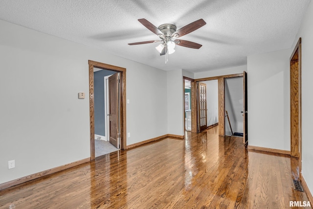 empty room featuring visible vents, a textured ceiling, baseboards, and wood finished floors