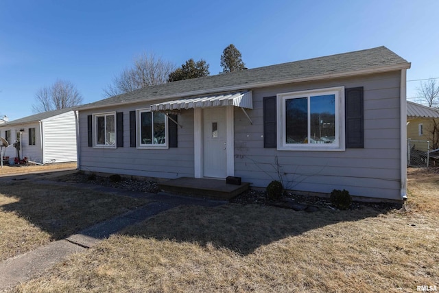 ranch-style house featuring a shingled roof and a front yard