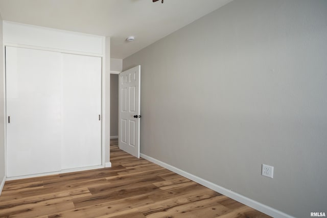 unfurnished bedroom with a closet, wood finished floors, and baseboards