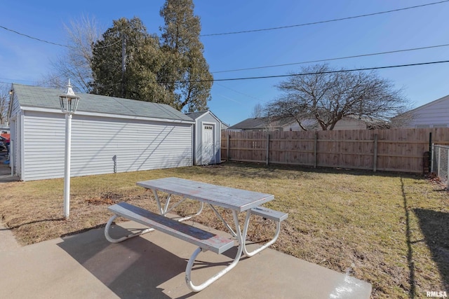 view of yard with a patio area, a fenced backyard, an outdoor structure, and a shed