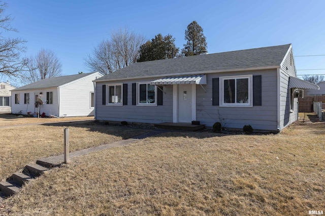 view of front of house with a shingled roof and a front lawn