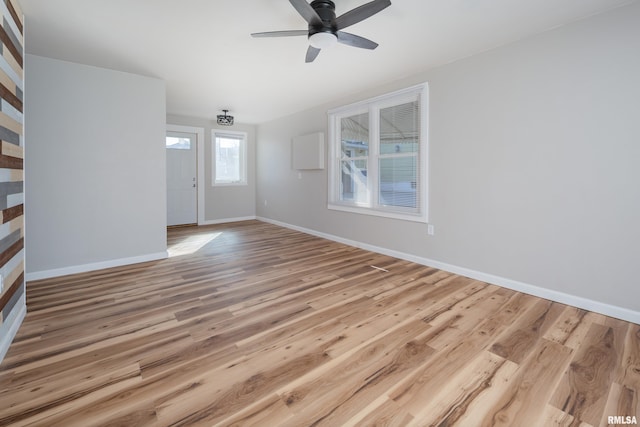 unfurnished living room featuring ceiling fan, wood finished floors, and baseboards