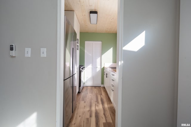 kitchen with white cabinetry, baseboards, light wood-style floors, light countertops, and appliances with stainless steel finishes