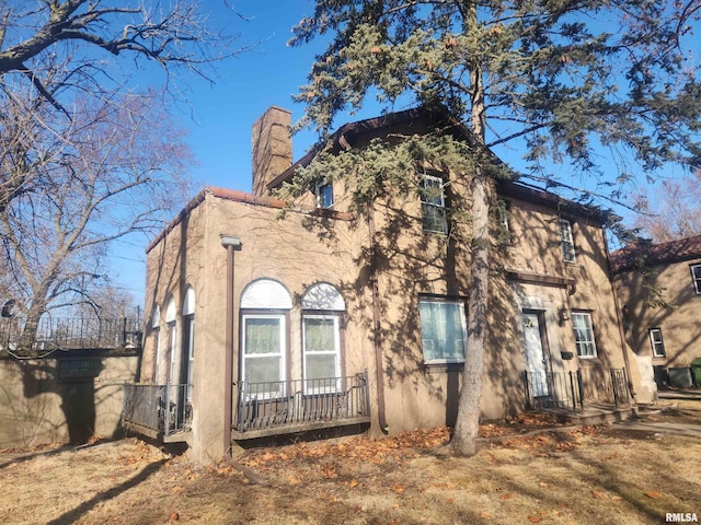 view of front of home with a chimney and stucco siding