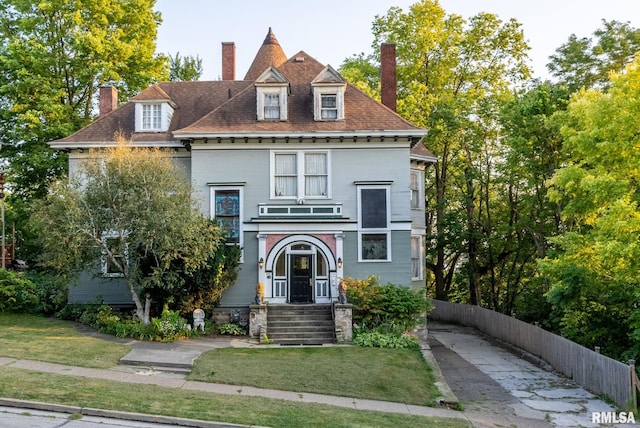 view of front facade with fence, a chimney, and a front lawn