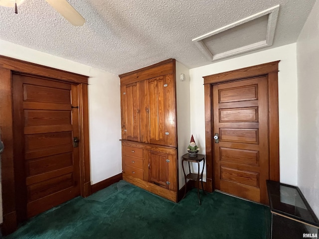 interior space with baseboards, dark carpet, and a textured ceiling