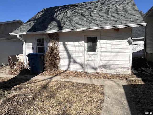 exterior space with an attached garage and roof with shingles