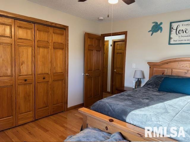 bedroom featuring a ceiling fan, a closet, light wood-style flooring, and a textured ceiling