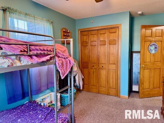 bedroom featuring carpet floors, a closet, a textured ceiling, and a ceiling fan