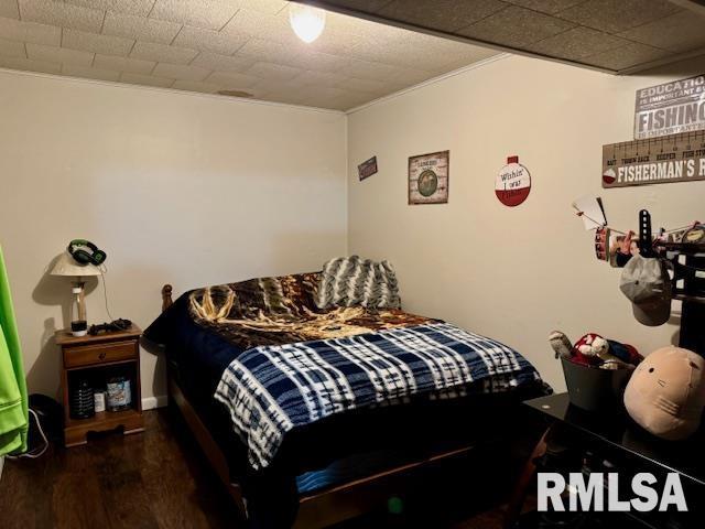 bedroom featuring ornamental molding and wood finished floors