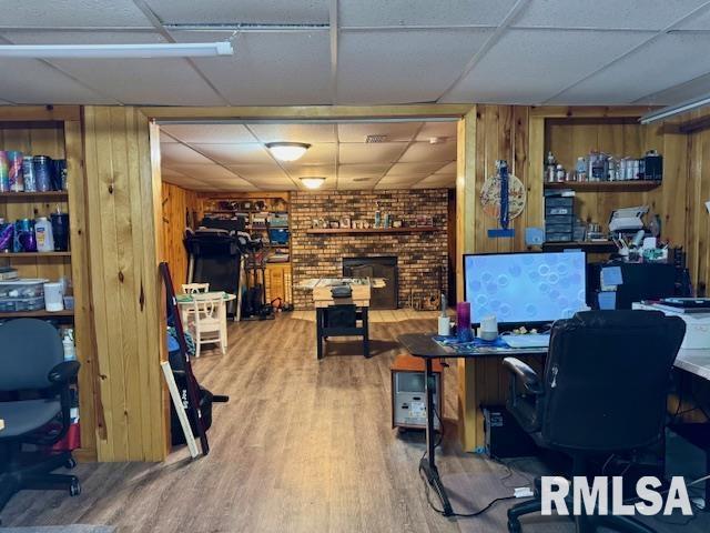 office area featuring wood finished floors, a paneled ceiling, and wooden walls