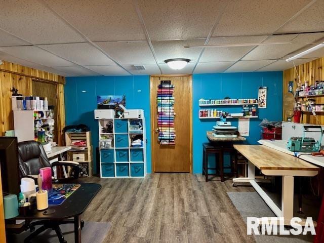 interior space with a drop ceiling and wood finished floors