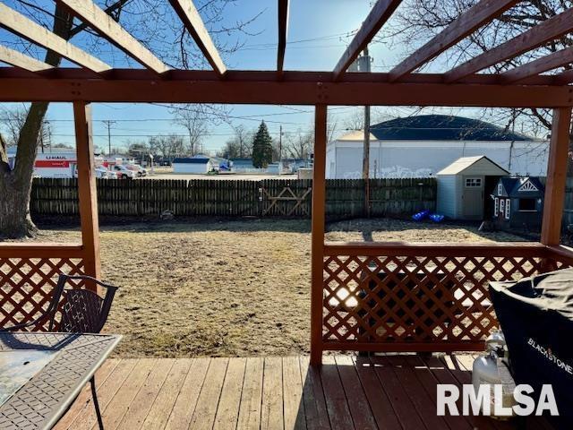 deck with an outbuilding, a pergola, a fenced backyard, and a shed