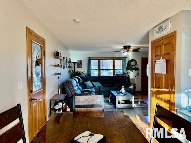 living room featuring ceiling fan, a textured ceiling, and wood finished floors